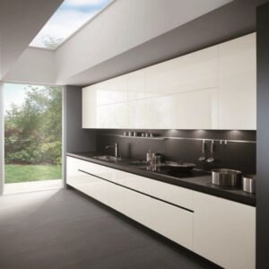 Modern minimalist kitchen with glossy white cabinets dark countertop and skylight.