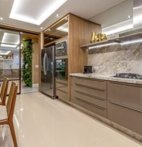 Light luxury kitchen with wood accented taupe cabinets marble backsplash and mirrored accents.