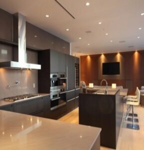 High-end luxury kitchen with dark gray cabinets wood accents and integrated appliances.