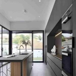 Modern minimalist kitchen with rattan-accented dark cabinets, large glass doors, airy layout.