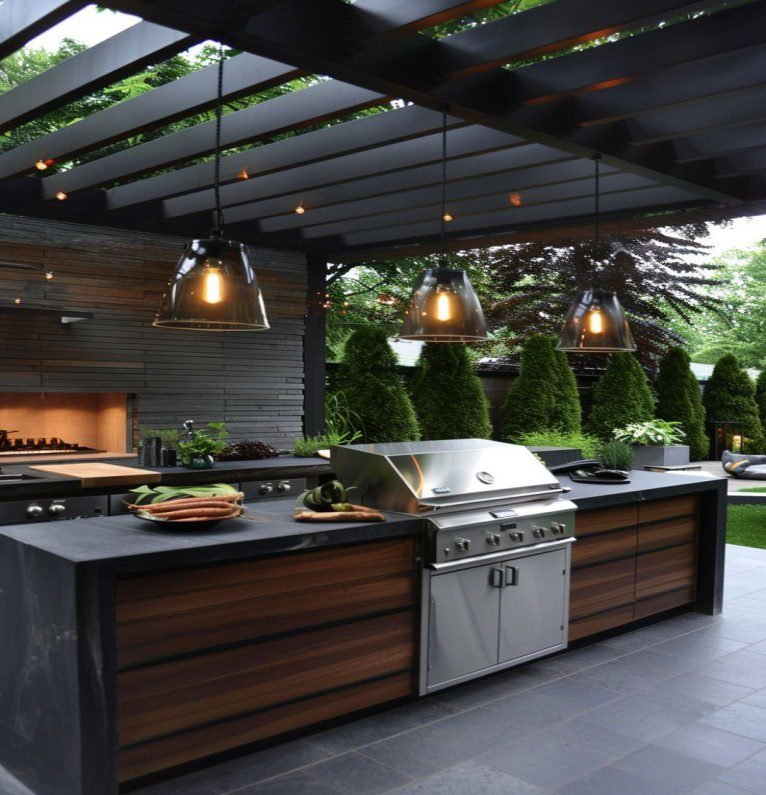 Outdoor nature kitchen with wood kitchen cabinets, stainless steel fixtures, and pendant lights.