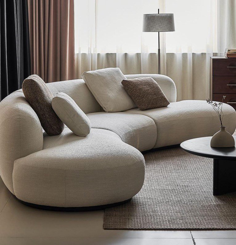 Beige Fabric Curved Sofa features soft texture, modern stylish, crafted with durable fabric, add cozy charm to contemporary living spaces.