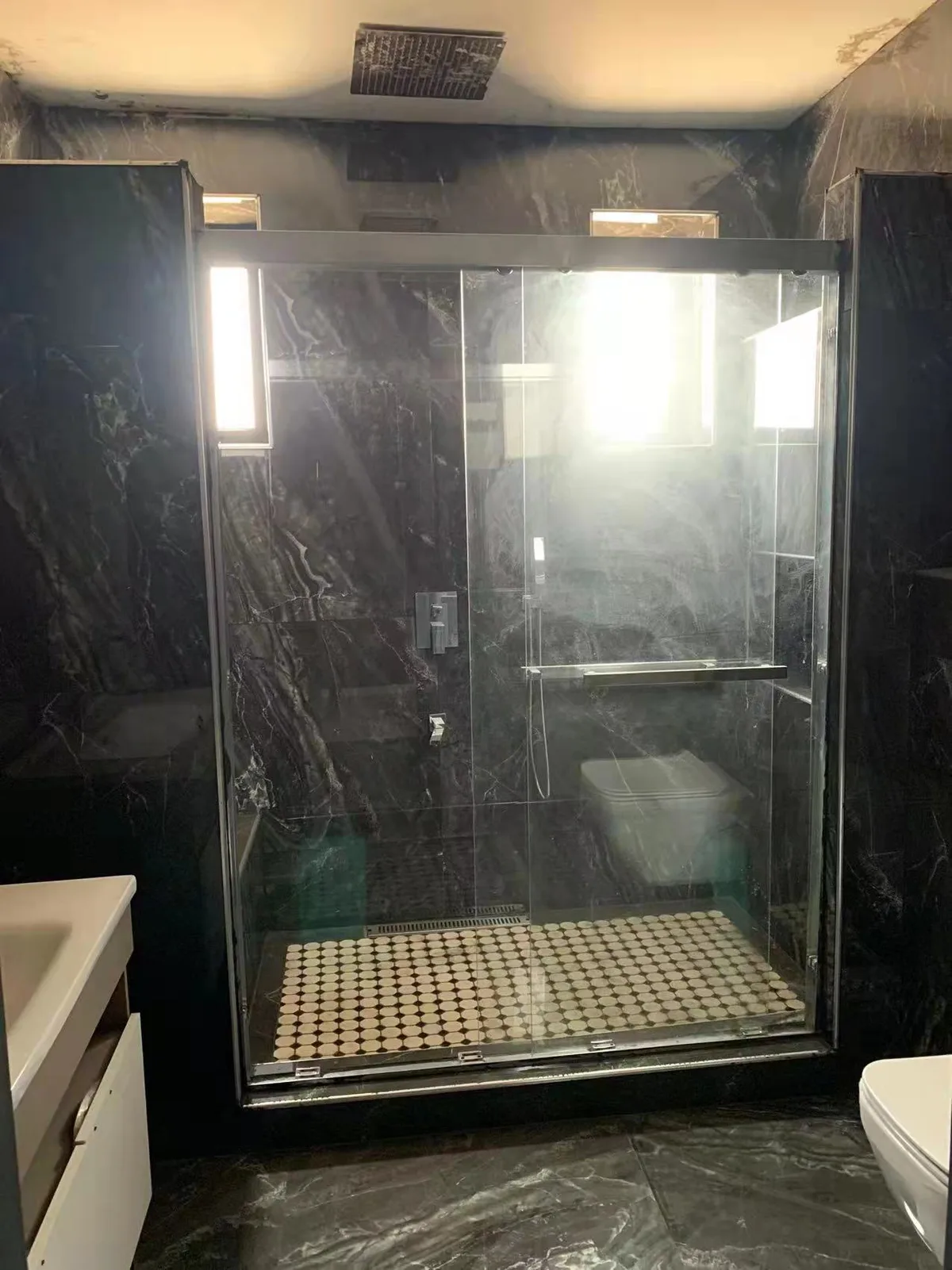 Dark-tiled shower enclosure with mosaic floor
