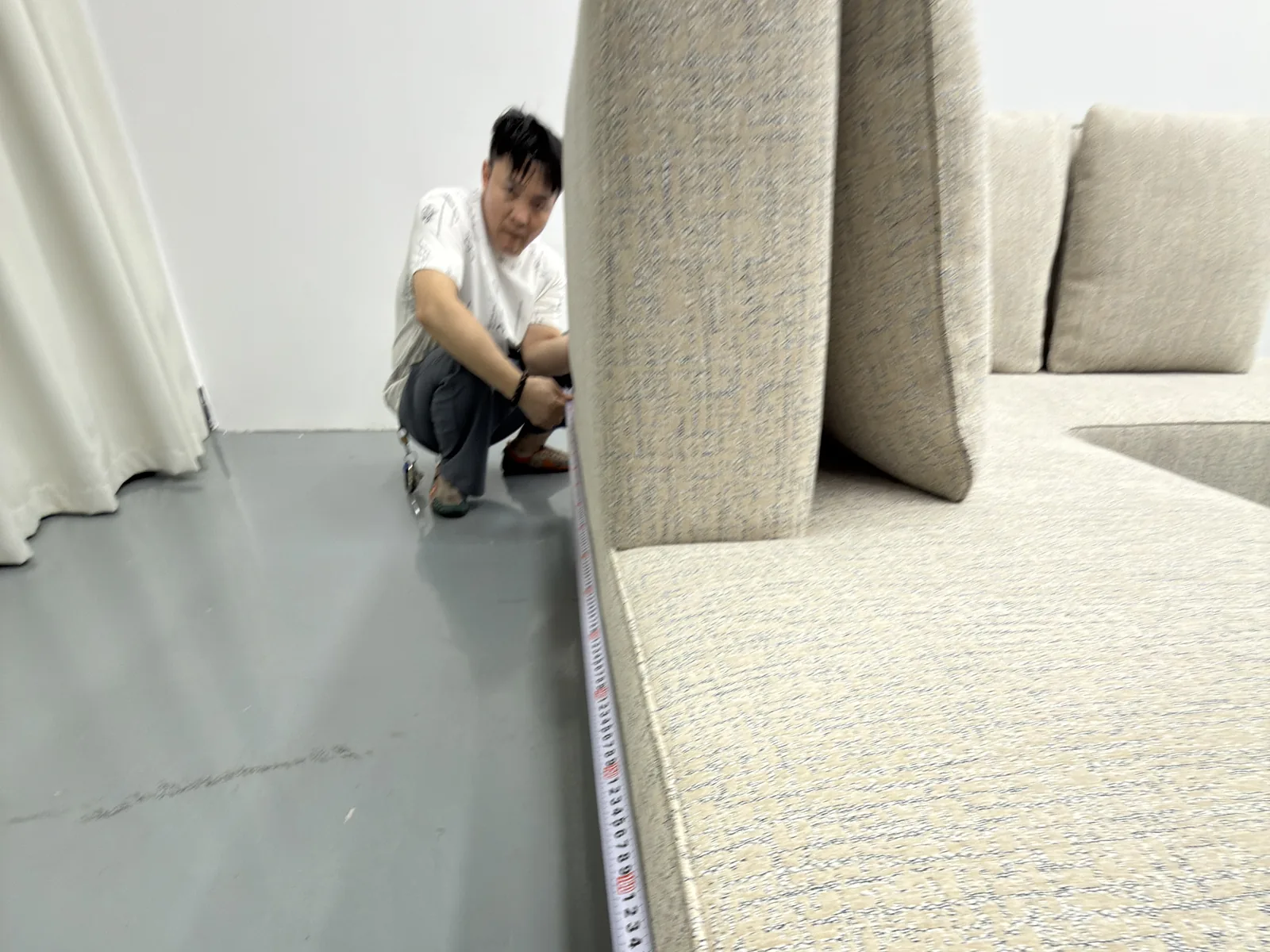 QC inspector measuring sofa length with a tape measure against approved drawings during pre-shipment inspection